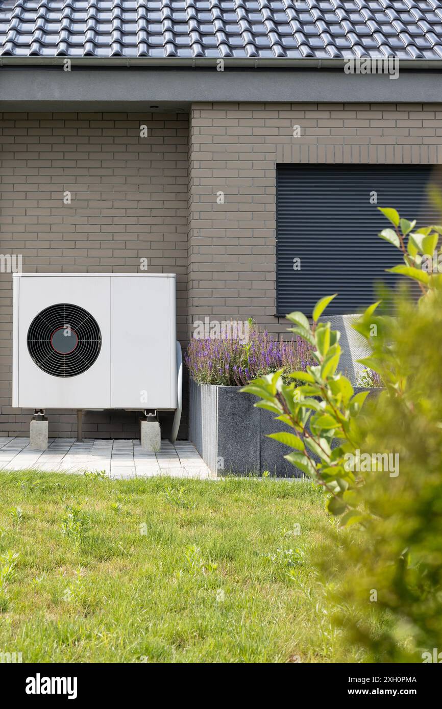 Pompe à chaleur moderne sur bâtiment en brique avec jardin Banque D'Images