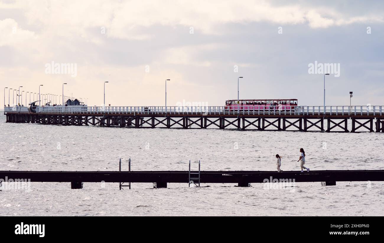 Le train à jetée sur la jetée de Busselton et deux enfants sur la jetée plus petite dans des conditions atmosphériques à Busselton estran, Australie occidentale. Banque D'Images