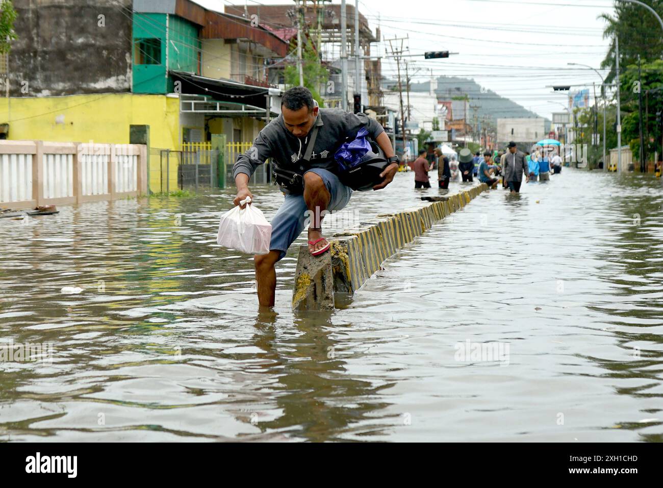 Gorontalo, Indonésie. 11 juillet 2024. Un homme patente dans les eaux de crue causées par de fortes pluies à Gorontalo, Indonésie, le 11 juillet 2024. Crédit : Malik/Xinhua/Alamy Live News Banque D'Images