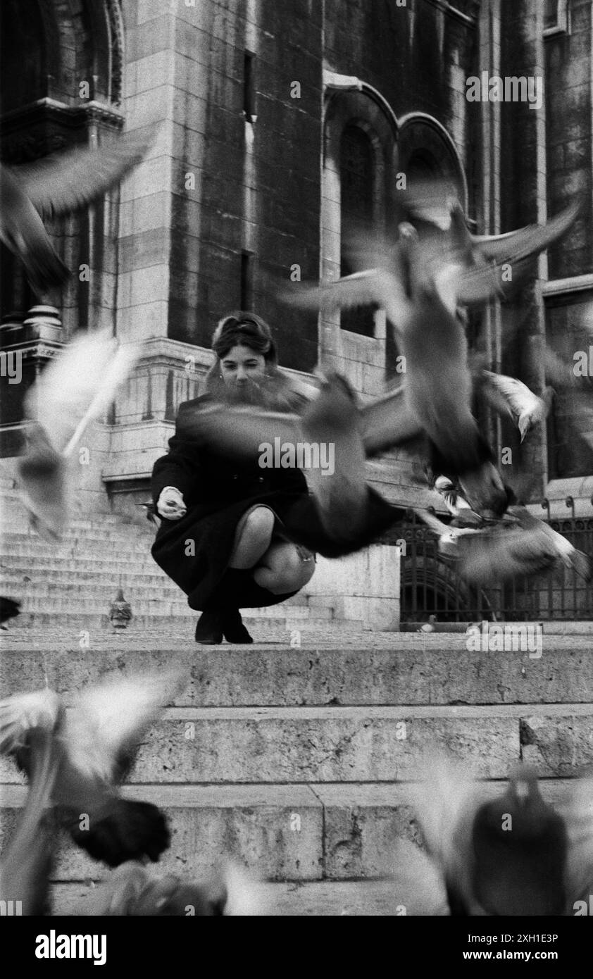 Jeune femme avec des pigeons sur les marches du Sacré coeur à Paris, vers 1965 Banque D'Images