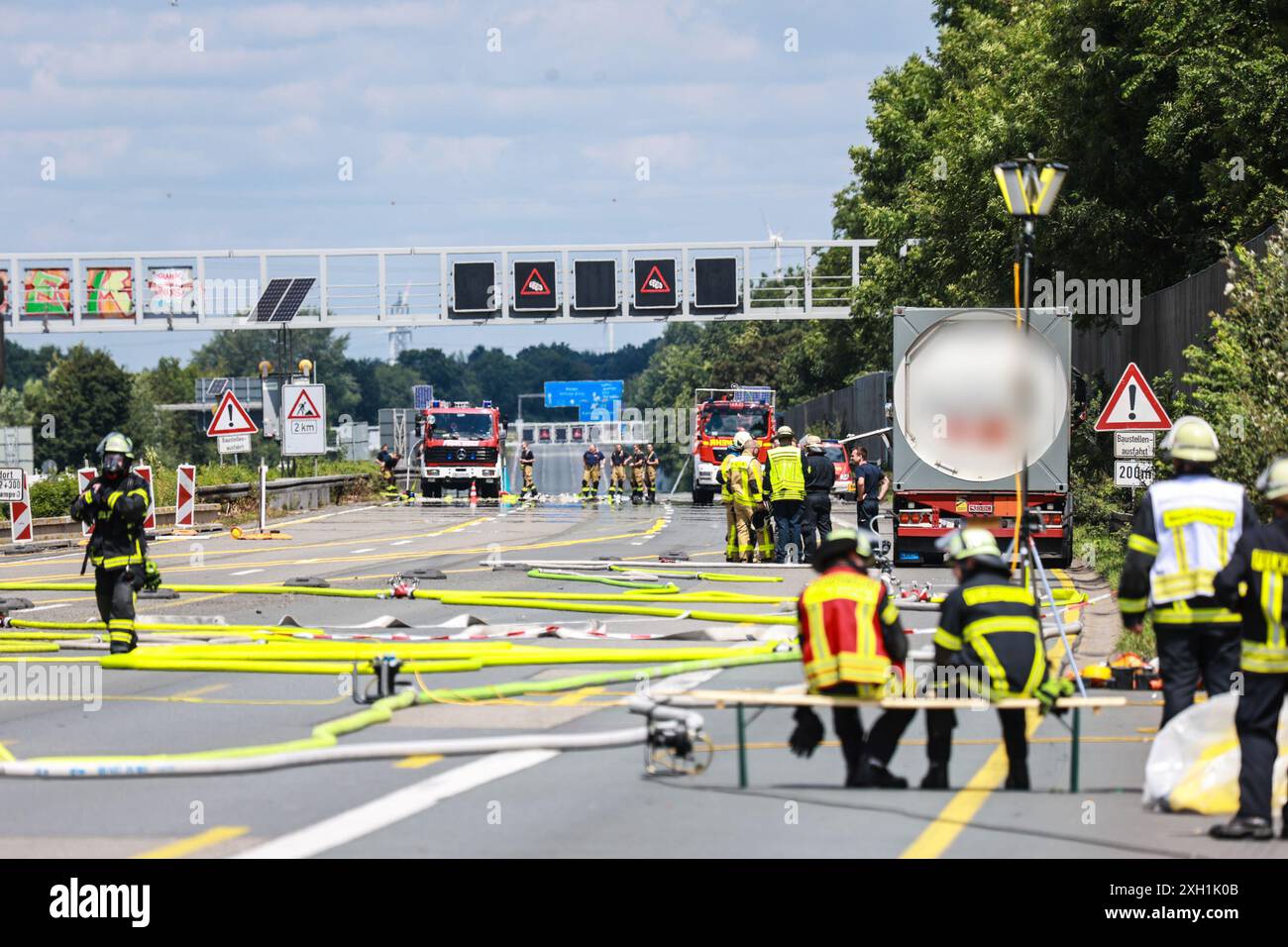 Unna, Allemagne. 11 juillet 2024. Les pompiers se trouvent sur l'autoroute A1 entre le carrefour Kamener Kreuz et Dortmund/Unna, près d'un camion de marchandises dangereuses (R) qui fuyait du gaz. La route a dû être fermée dans les deux sens en raison de la fuite du réservoir du camion. Crédit : Alex Talash/dpa - ATTENTION : le nom de l'entreprise et la plaque d'immatriculation du camion-citerne ont été pixelisés pour des raisons légales/dpa/Alamy Live News Banque D'Images