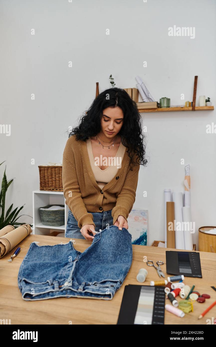 Une jeune femme qui met à jour un Jean de façon créative à une table. Banque D'Images