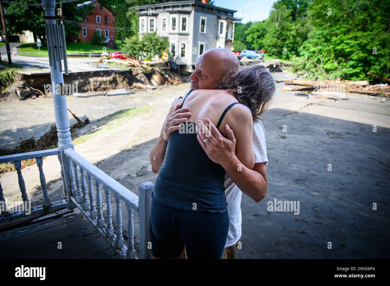 Plainfield, Vermont, États-Unis. 11 juillet 2024. Jim et Jenni Belotserkovsky s'embrassent après que leur maison a été inondée lorsque des pluies torrentielles des restes de l'ouragan Beryl ont frappé le centre du Vermont, aux États-Unis, le 10 juillet. Great Brook, un affluent de la rivière Winooski, a miné la maison au loin derrière eux, qui n'est pas leur maison mais la leur est à proximité sur le ruisseau. John Lazenby/Alamy Live News Banque D'Images