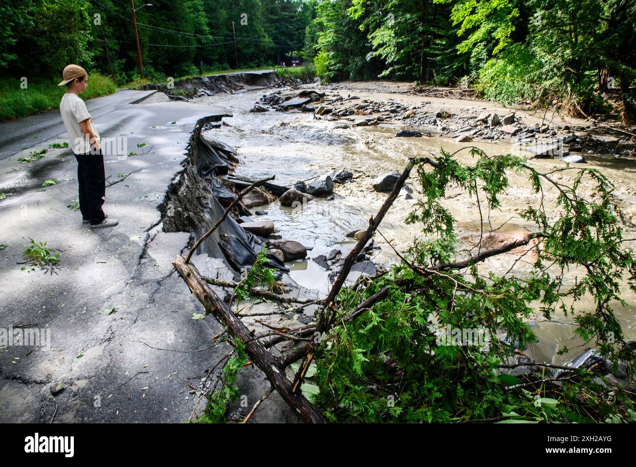 Plainfield, Vermont, États-Unis. 11 juillet 2024. Un garçon debout sur les restes de Brook Road regarde Great Brook après que des pluies torrentielles des restes de l'ouragan Beryl ont frappé le centre du Vermont, aux États-Unis. John Lazenby/Alamy Live News Banque D'Images