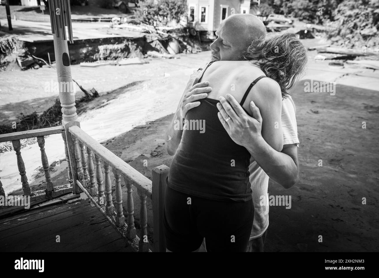 Plainfield, Vermont, États-Unis. 11 juillet 2024. Jim et Jenni Belotserkovsky s'embrassent après que leur maison a été inondée lorsque des pluies torrentielles des restes de l'ouragan Beryl ont frappé le centre du Vermont, aux États-Unis, le 10 juillet. Great Brook, un affluent de la rivière Winooski, a miné la maison au loin derrière eux, qui n'est pas leur maison mais la leur est à proximité sur le ruisseau. John Lazenby/Alamy Live News Banque D'Images