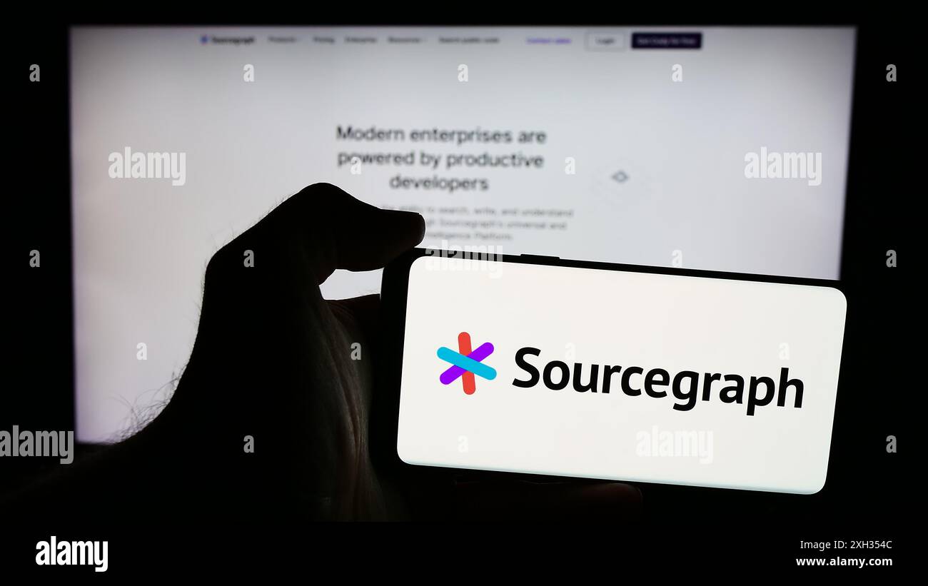Personne tenant le téléphone portable avec le logo de la société américaine de renseignement de code Sourcegraph Inc en face de la page Web. Concentrez-vous sur l'affichage du téléphone. Banque D'Images