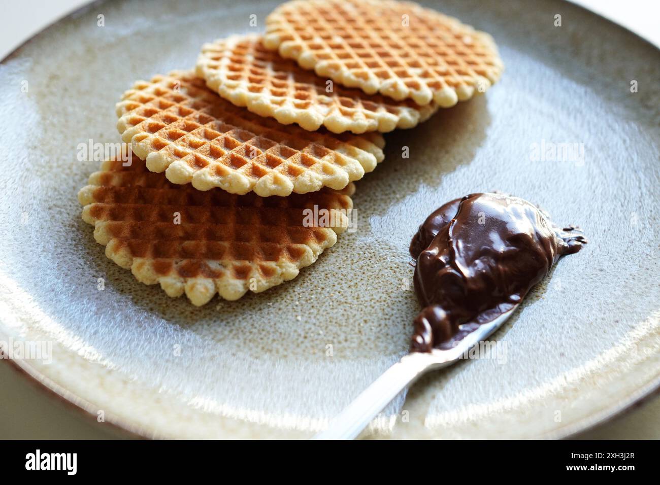 Biscuits gaufrés ronds et crème au chocolat sur une assiette avec un fond blanc Banque D'Images