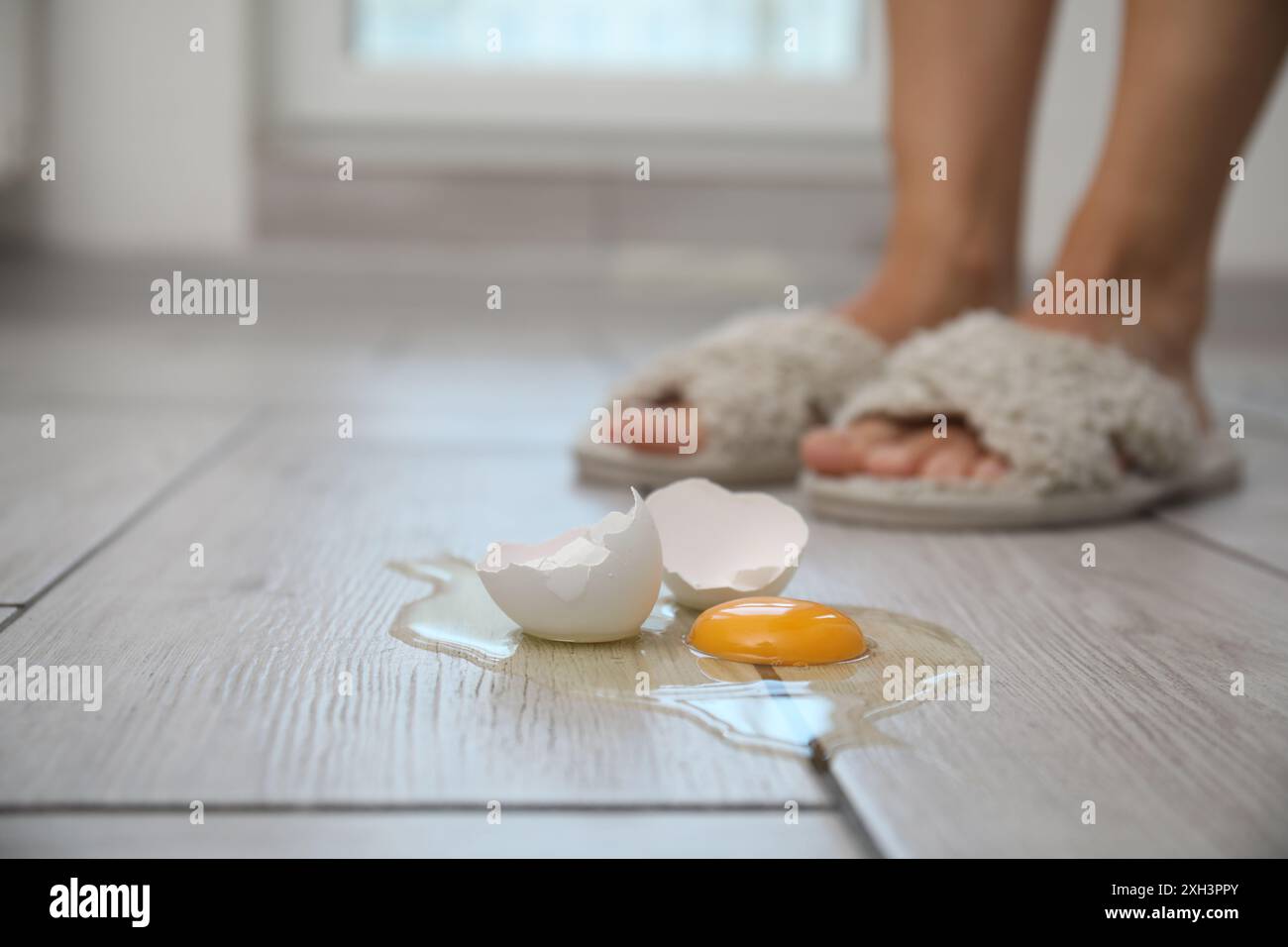 Femme près de l'oeuf cru cassé sur plancher en bois gris à l'intérieur, foyer sélectif. Espace pour le texte Banque D'Images