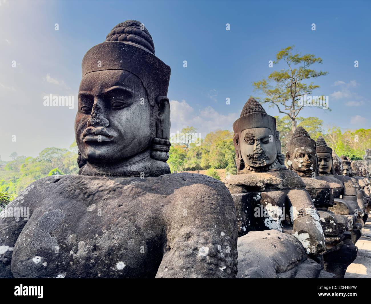 Le pont vers Angkor Thom, bordé des deux côtés de figurines se terminant par une entrée en arc encorbée, Cambodge. Banque D'Images Le pont vers Angkor Thom, bordé des deux côtés de figurines se terminant par une entrée en arc encorbée, Cambodge. Banque D'Images