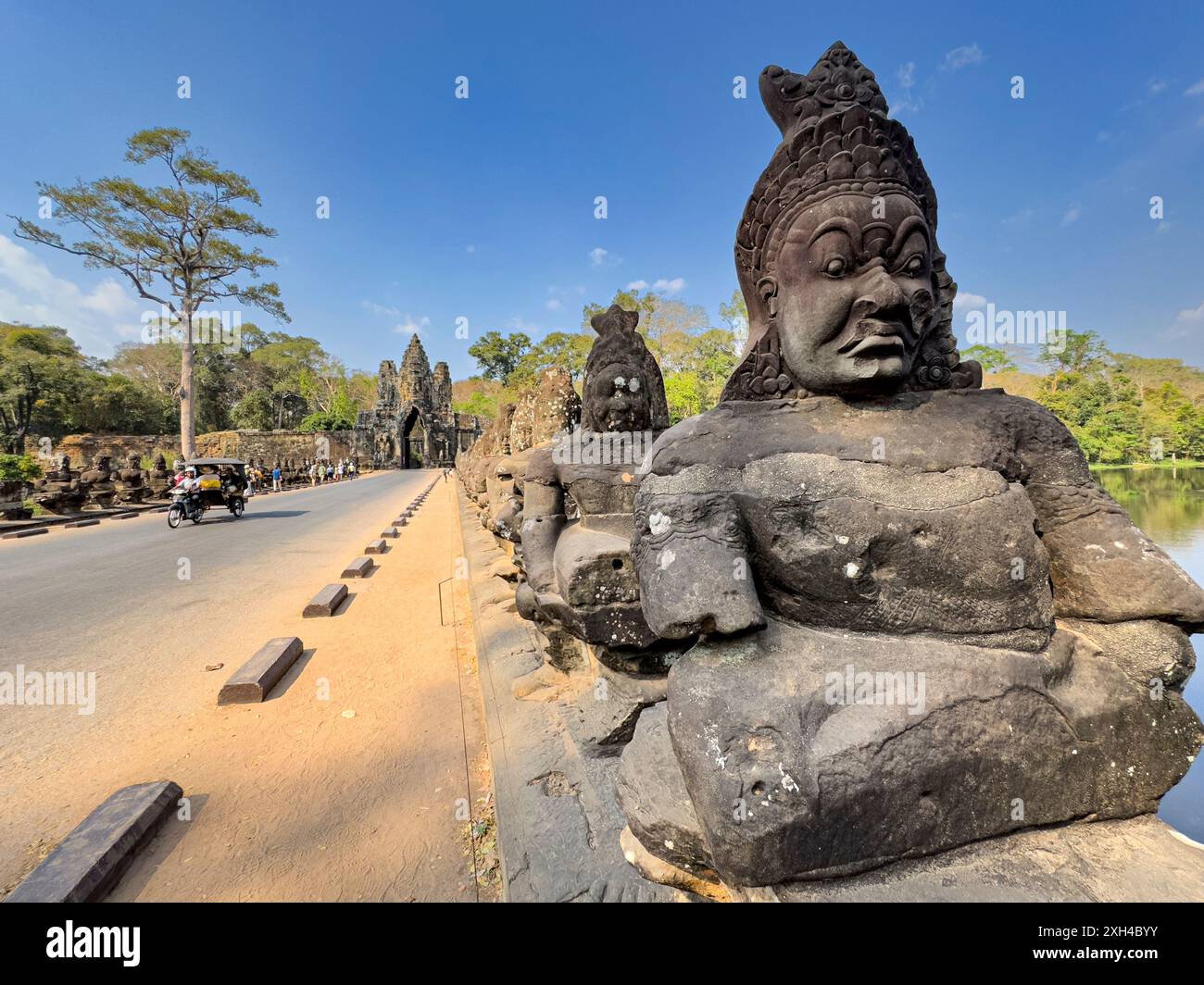 Le pont vers Angkor Thom, bordé des deux côtés de figurines se terminant par une entrée en arc encorbée, Cambodge. Banque D'Images Le pont vers Angkor Thom, bordé des deux côtés de figurines se terminant par une entrée en arc encorbée, Cambodge. Banque D'Images