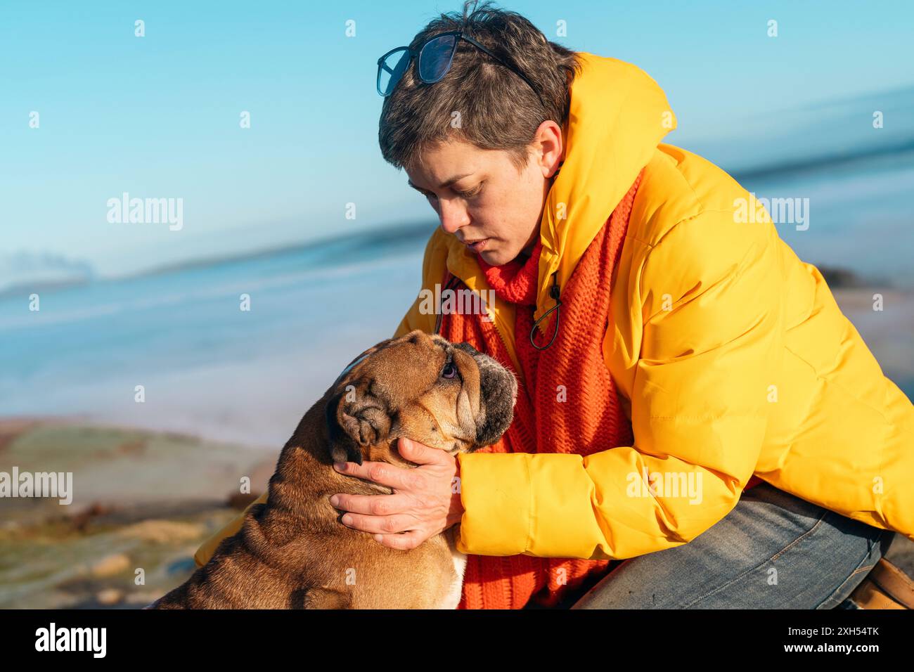 femme mature en veste jaune randonnée dans les montagnes avec chien, exercice et remise en forme pour le bien-être, un style de vie sain et le sourire. Femelle mature avec bulldo Banque D'Images