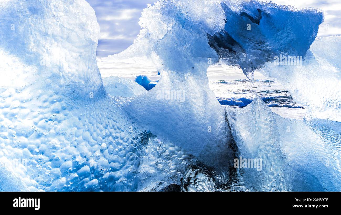 Grande formation de glace sur la côte. A travers ses irrégularités, vous pouvez voir l'océan. La glace brille dans différentes nuances de bleu. Banque D'Images