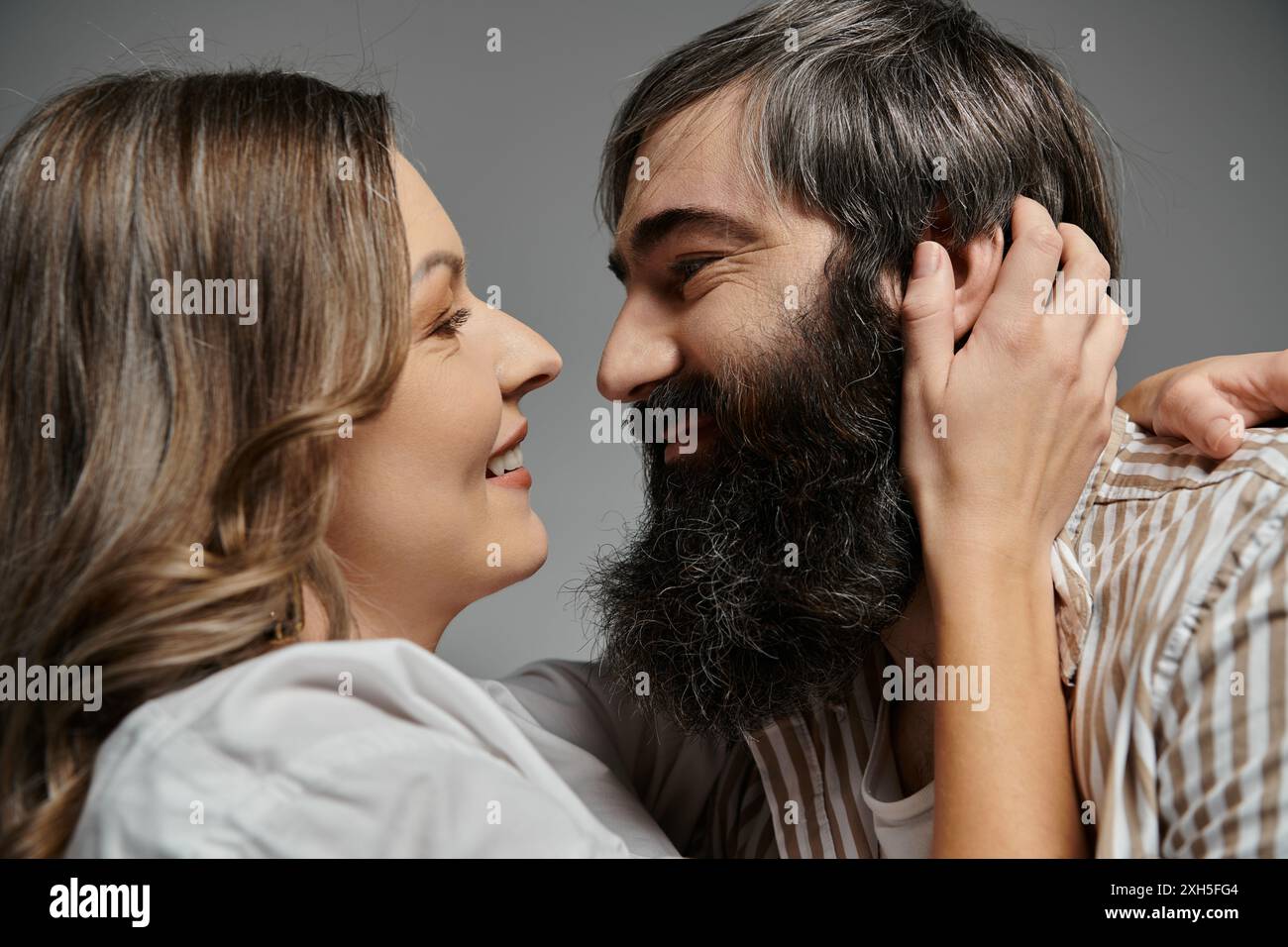 Un couple en tenue élégante, avec un accent sur leurs expressions aimantes, partageant un moment tendre. Banque D'Images