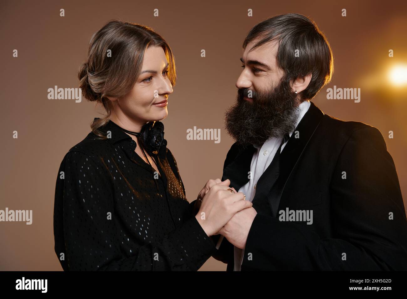 Un couple aimant, vêtu d'une tenue élégante, pose ensemble, les yeux enfermés dans un regard tendre. Banque D'Images