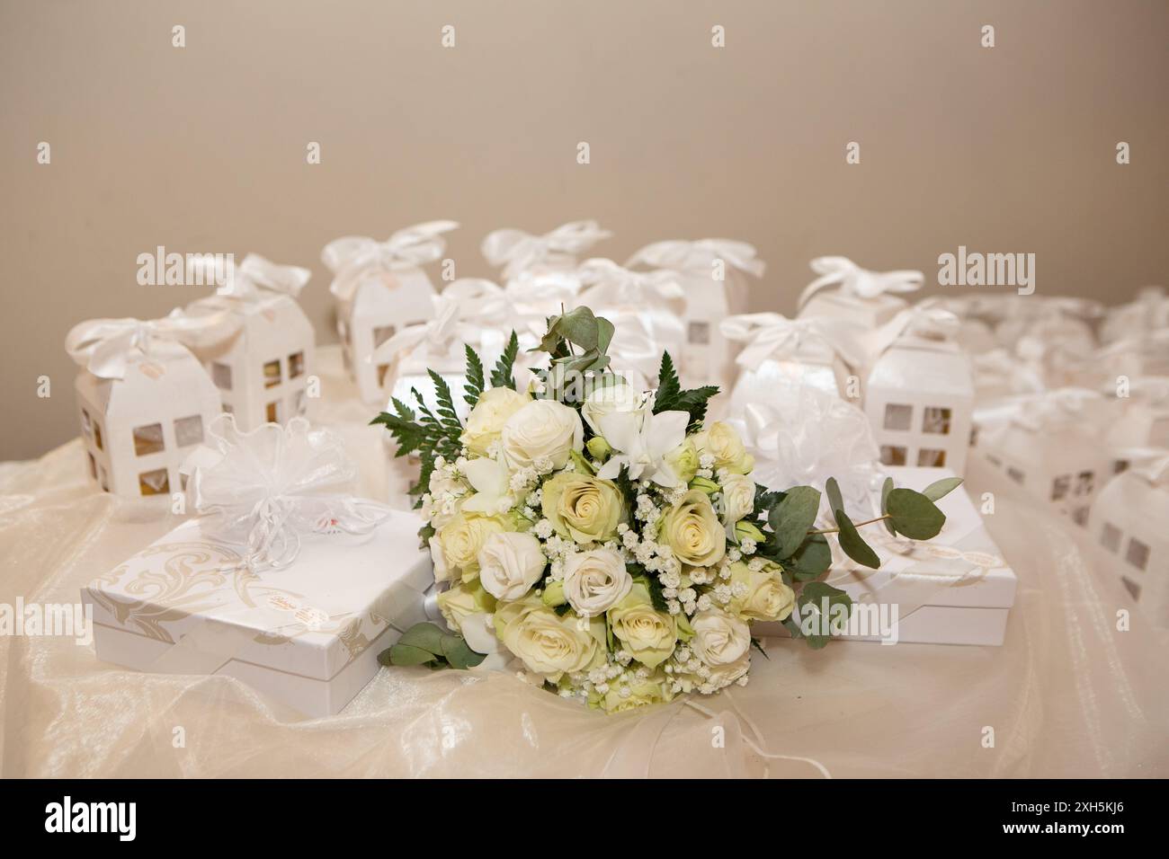 Roses blanches et bouquet de souffle de bébé couché sur la table près des faveurs de mariage Banque D'Images