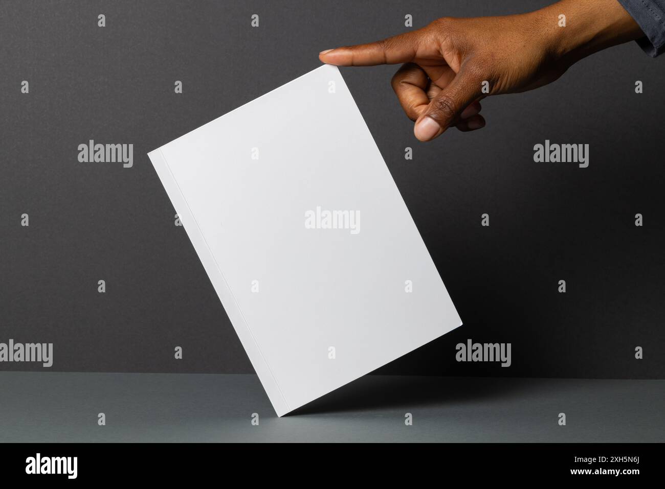 Main afro-américaine présentant un livret vierge, avec espace de copie. Idéal pour la publicité ou le branding, le livret offre amplement d'espace pour le texte ou le graphique Banque D'Images