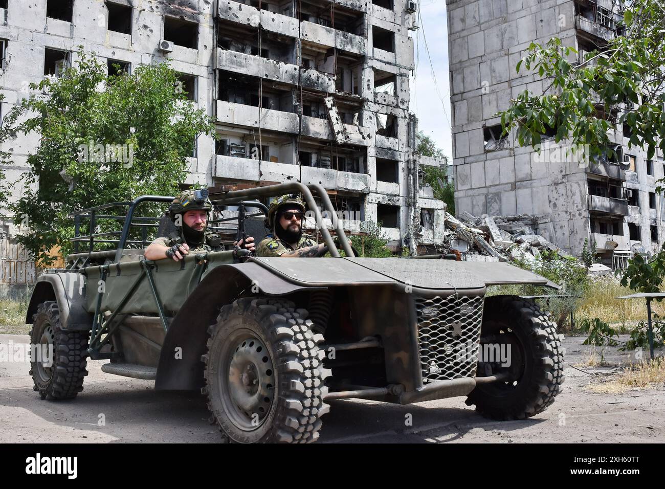 Des soldats ukrainiens de l'équipe d'évacuation de la 65e brigade mécanisée séparée conduisent dans le buggy d'évacuation près d'un immeuble d'appartements fortement endommagé par les bombardements russes à Orikhiv. Les défenseurs ukrainiens utilisent des buggies de plage, des VTT (véhicule tout-terrain) et des vélos électriques à l'avant parce que ces véhicules sont plus silencieux et plus difficiles à voir et à entendre. Cela donne aux soldats sur la ligne de front une meilleure chance d'éviter les drones russes et de survivre. Ces petits véhicules ne se substituaient pas aux véhicules militaires traditionnels. Ils manquent de puissance de feu et d'espace pour transporter un grand nombre de personnes ou de marchandises, Banque D'Images