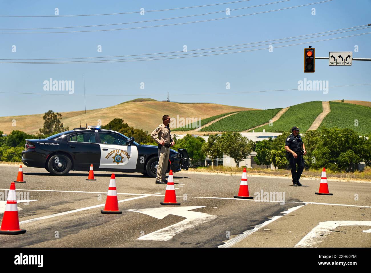 Californie, États-Unis d'Amérique - 12 juin 2024 : des policiers contrôlent la circulation à un carrefour en Californie, États-Unis. La fermeture de la route est surveillée par des responsables de la California Highway Patrol, avec des cônes de circulation et des véhicules de police assurant la sécurité *** Polizeikräfte kontrollieren den Verkehr an einer Kreuzung à Kalifornien, États-Unis. Die Straßensperrung wird durch offizielle der California Highway Patrol überwacht, wobei Verkehrshütchen und Polizeifahrzeuge für Sicherheit sorgen Banque D'Images