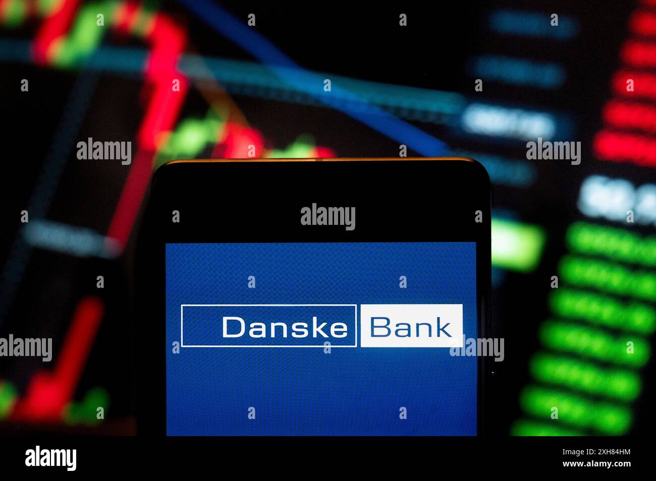 Dans cette illustration photo, le logo danois de la Danske Bank (CPH : DANSKE) vu sur un smartphone avec un graphique de l'indice boursier économique en arrière-plan. Banque D'Images