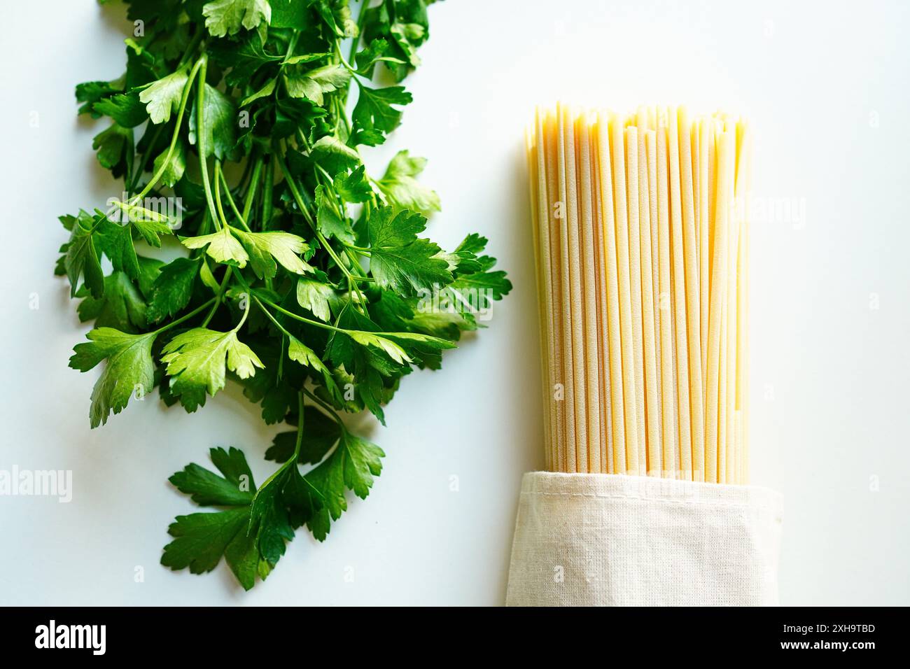 Persil italien et spaghetti sur fond blanc Banque D'Images