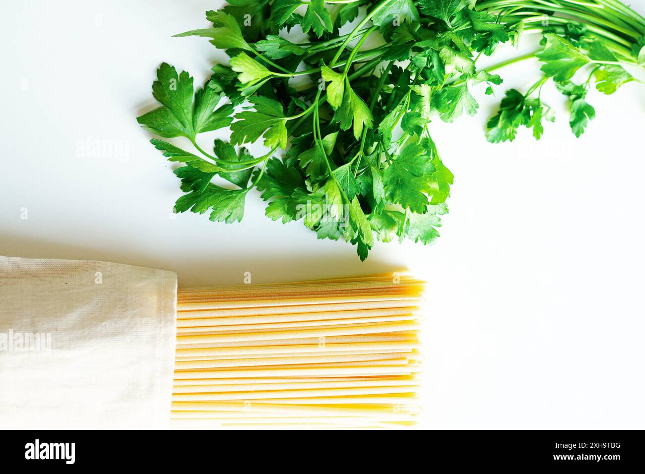 Persil italien et spaghetti sur fond blanc Banque D'Images