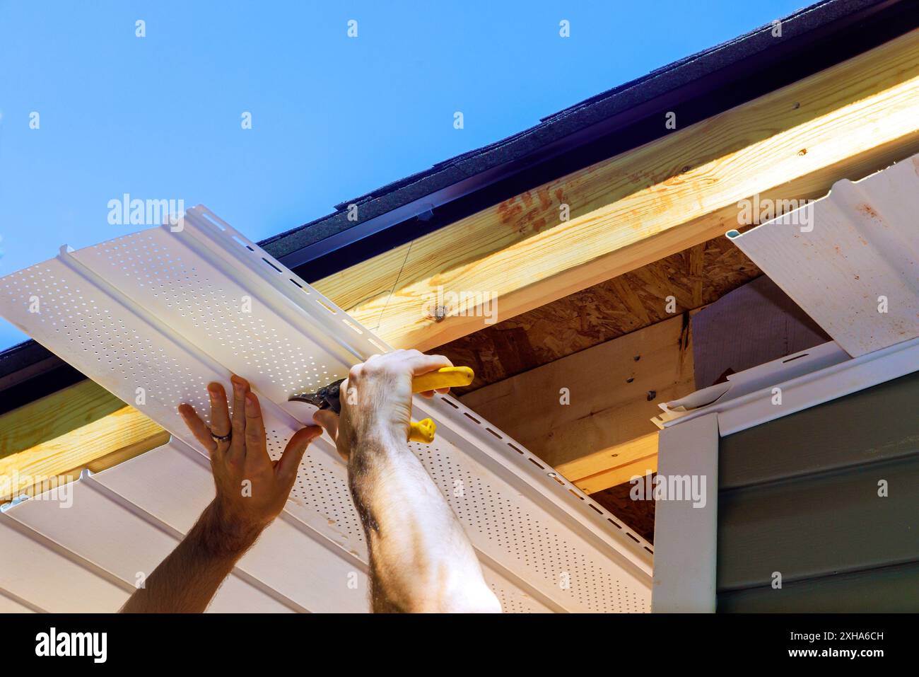 Panneaux en plastique de soffite de vinyle dans le plafond de façade de la nouvelle maison par un employé Banque D'Images