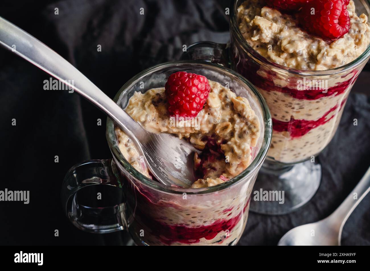 Framboise Peanut Butter Parfaits d'avoine avec cuillère : petit déjeuner en couches sain avec framboises, roulés de bouts, fruits et graines de chia dans des verres à café irlandais Banque D'Images