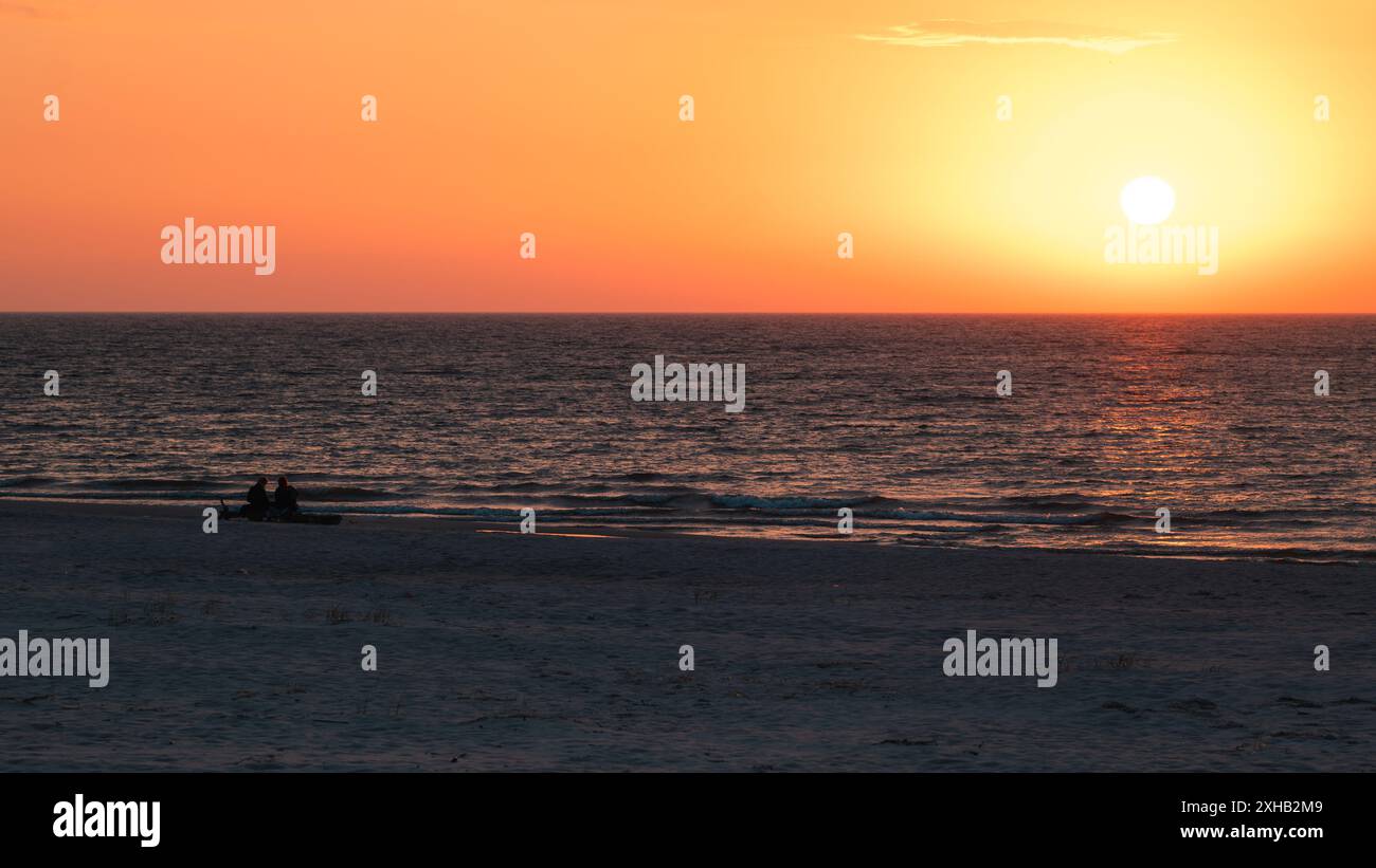 Magnifique coucher de soleil sur la mer Baltique. Silhouettes de deux personnes sur la plage regardant le coucher du soleil. Slajszewo, Pologne Banque D'Images