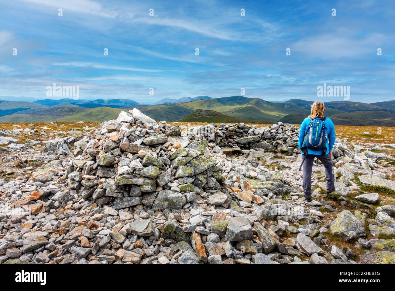 Walker au sommet cairn et abri en pierre de la montagne munro de Carn A Gheoidh, l'un des Cairnwell Munros à Glenshee, Aberdeenshire, Écosse Banque D'Images