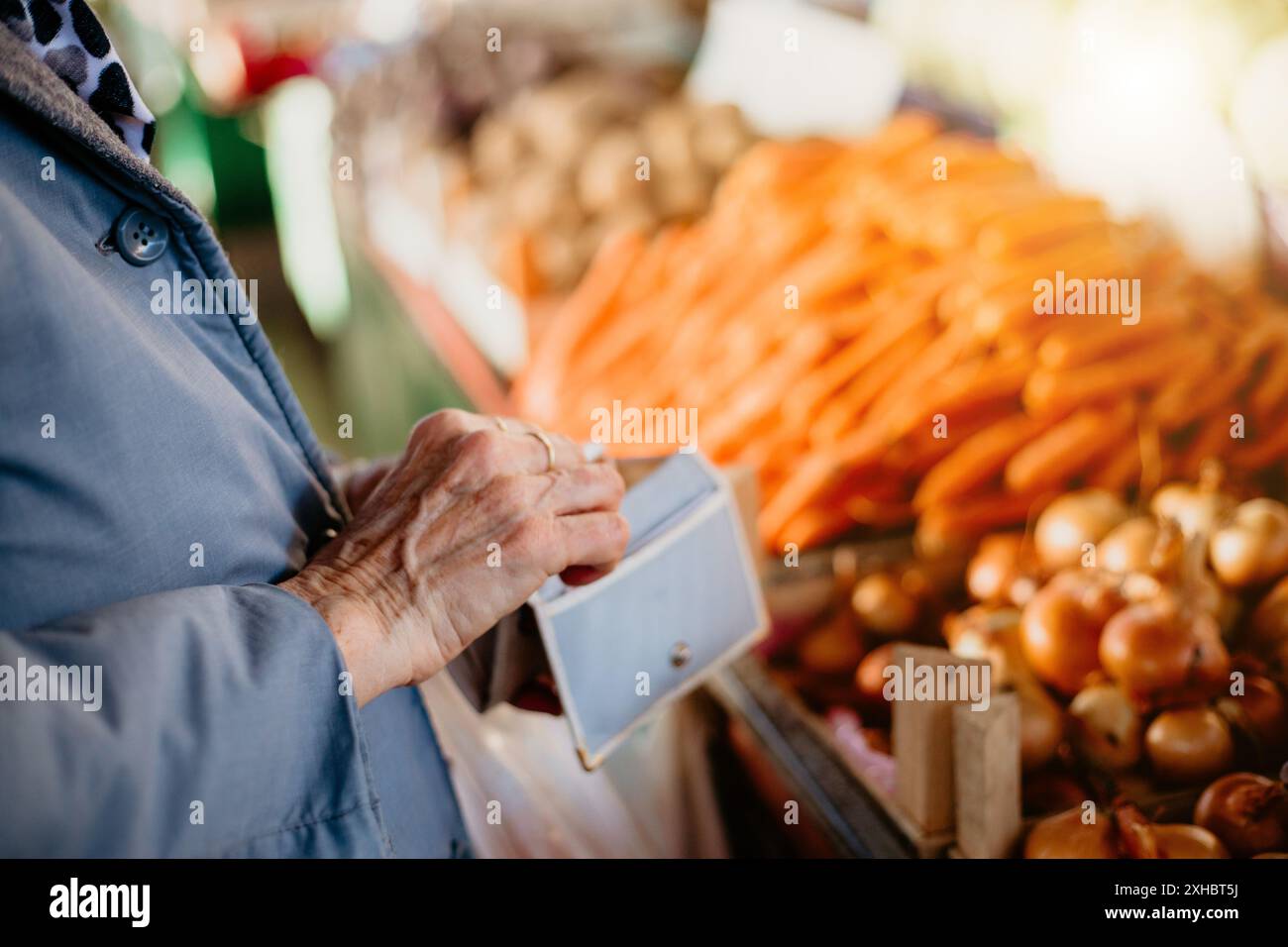 Une femme âgée avec sa main dans son portefeuille, se préparant à payer pour des produits au marché. Banque D'Images