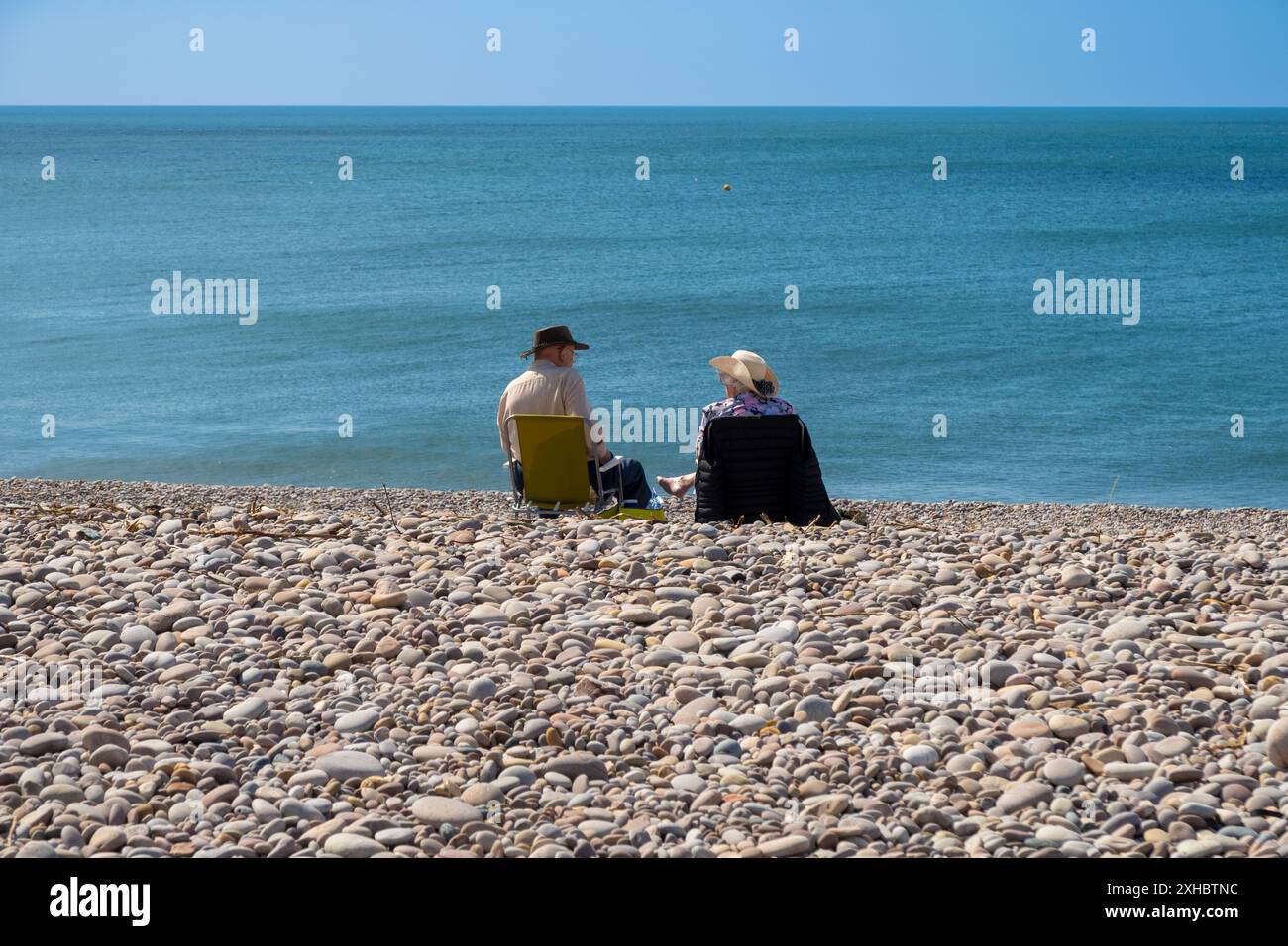 Couple assis sur la plage de Budleigh Salterton, Devon, Royaume-Uni Banque D'Images