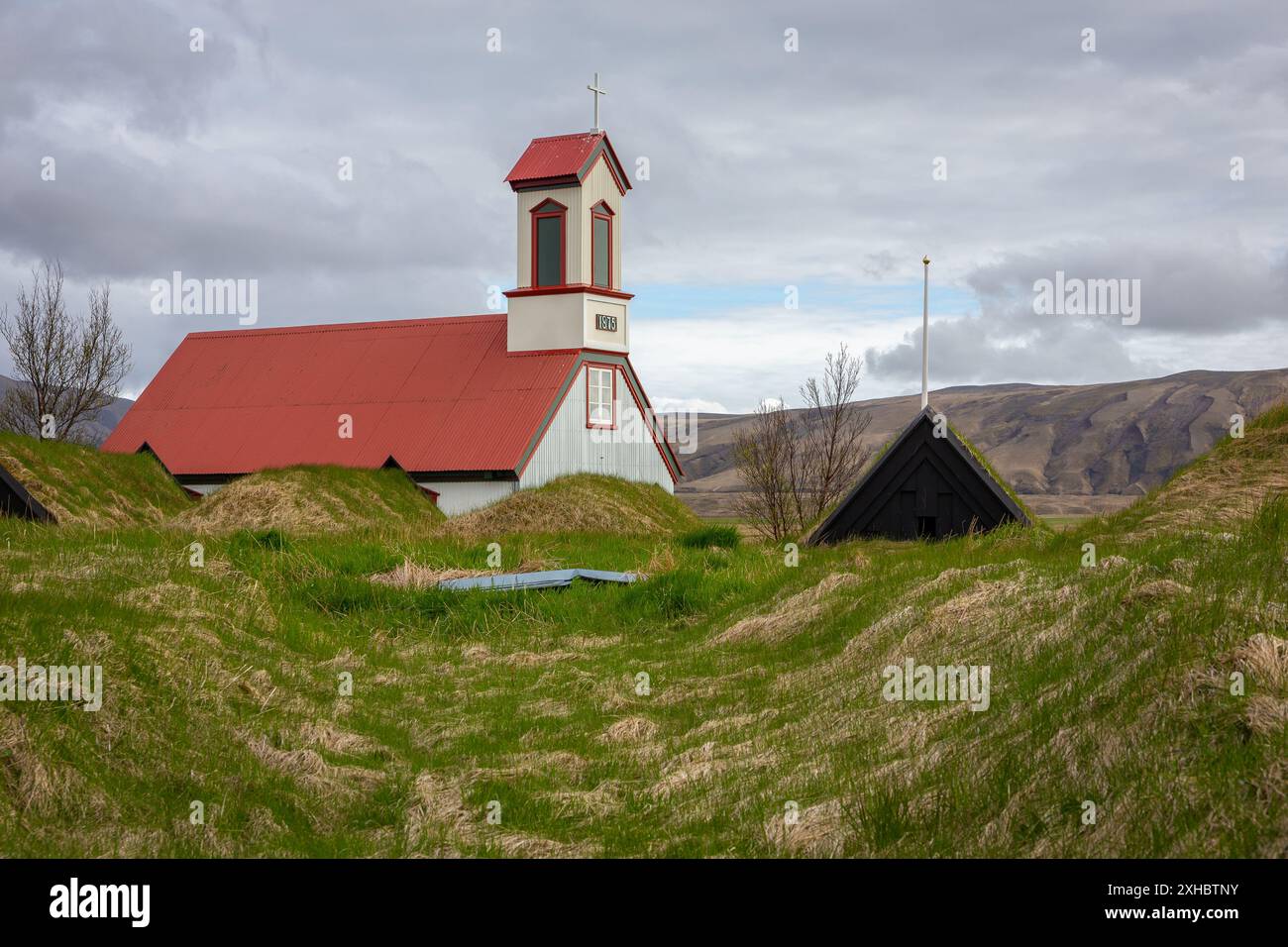 Ferme Keldur en Islande avec l'église Keldnakirkja de 1875 et rangée de vieilles maisons de gazon envahies d'herbe et de mousse. Banque D'Images