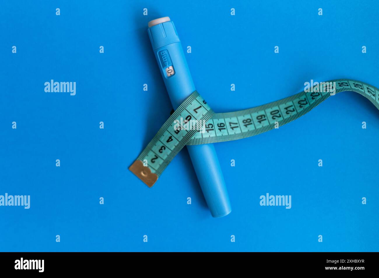 Ozempic injecteur médicamenteux avec ruban à mesurer sur fond bleu. Anti-diabète et baisse du taux de sucre dans le sang. Concept de perte de poids Banque D'Images
