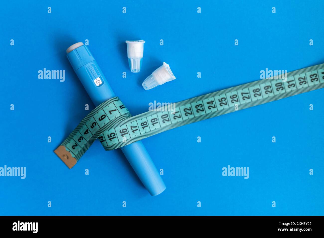 Injection moderne de stylo de drogue Ozempic pour la perte de poids avec ruban à mesurer corporel et aiguilles sur un fond bleu. médicament pour réduire le sucre et diabétiques. Banque D'Images