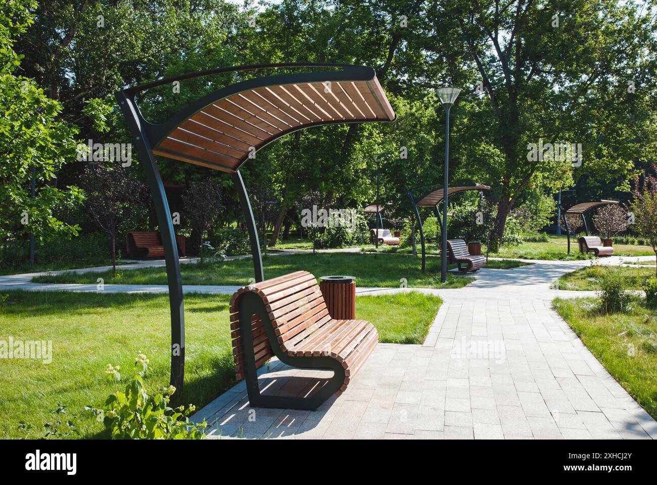 Parc public de la ville avec bancs en bois, bacs à litière et sentiers pavés, pas de personnes Banque D'Images