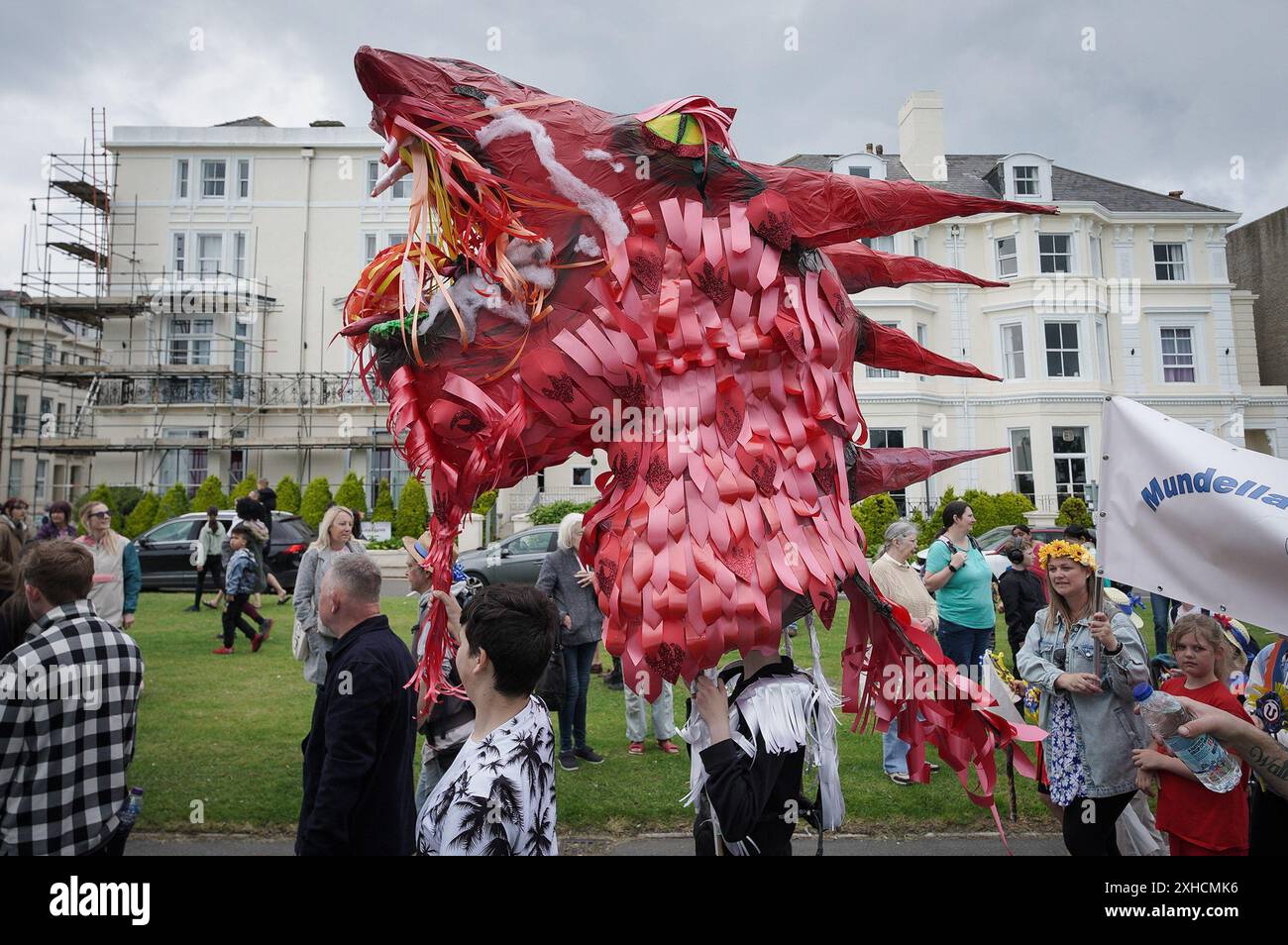 Folkestone, Kent, Royaume-Uni. 13 juillet 2024. Défilé annuel du Charivari Day. Folklore britannique et traditions rituelles sont le thème de la saisissante parade du carnaval de cette année. Des sculptures massives de tête ornent les épaules des jeunes locaux avec des enfants de l'école primaire à travers le district habillant aux couleurs du thème de l'année. Marchant du stade, en passant par la ville jusqu’au kiosque à musique Leas, le Charivari Day reste la plus grande tradition coutumière de Folkestone depuis 1997 et attire des centaines de spectateurs dans la ville portuaire en bord de mer. Crédit : Guy Corbishley/Alamy Live News Banque D'Images