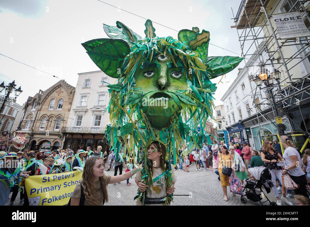 Folkestone, Kent, Royaume-Uni. 13 juillet 2024. Défilé annuel du Charivari Day. Folklore britannique et traditions rituelles sont le thème de la saisissante parade du carnaval de cette année. Des sculptures massives de tête ornent les épaules des jeunes locaux avec des enfants de l'école primaire à travers le district habillant aux couleurs du thème de l'année. Marchant du stade, en passant par la ville jusqu’au kiosque à musique Leas, le Charivari Day reste la plus grande tradition coutumière de Folkestone depuis 1997 et attire des centaines de spectateurs dans la ville portuaire en bord de mer. Crédit : Guy Corbishley/Alamy Live News Banque D'Images