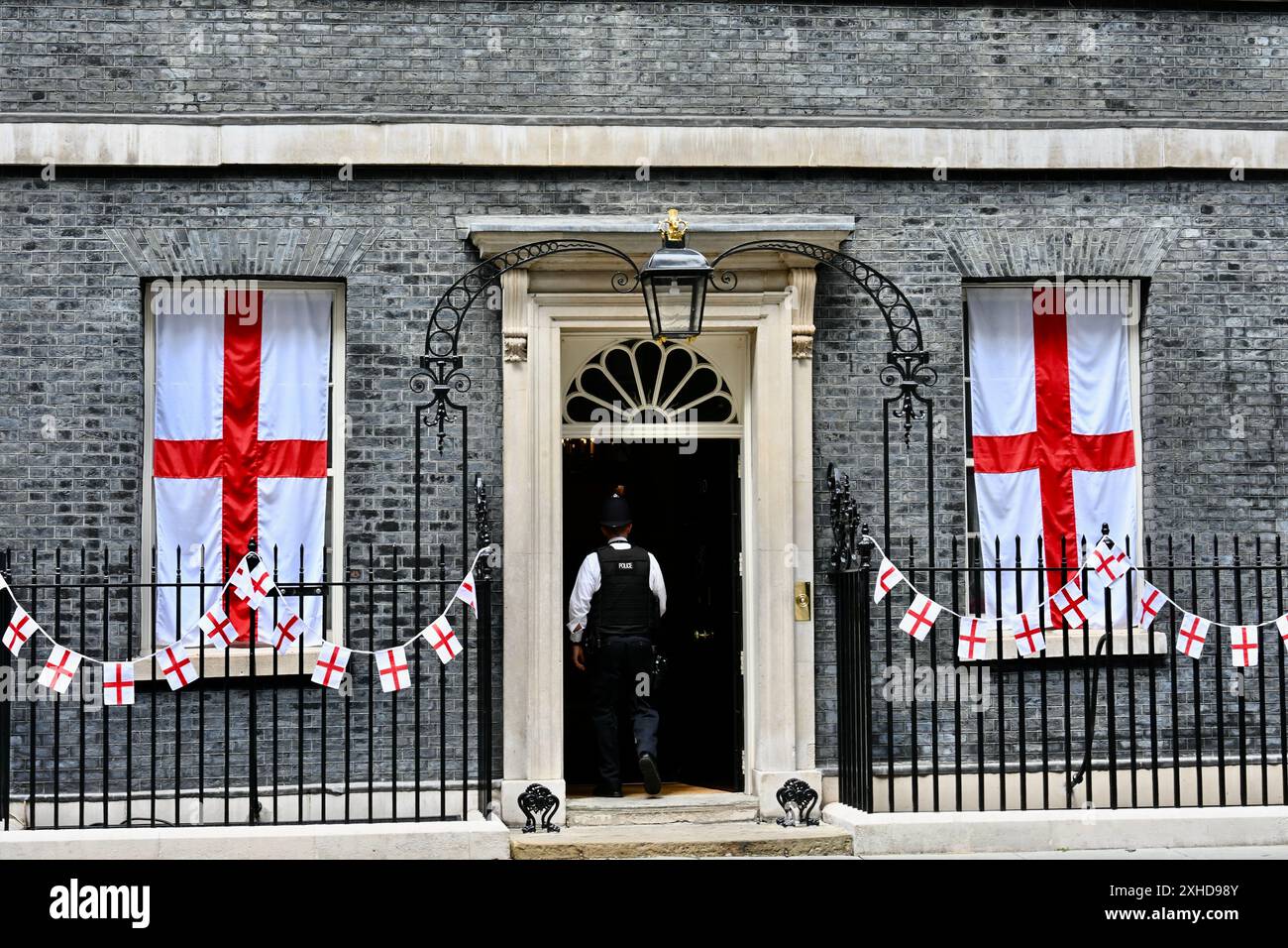 Un policier entre au 10 Downing Street à la veille de la finale de l'Euro 2024 Angleterre contre Espagne. Downing Street a été décorée de drapeaux anglais en soutien à l'équipe nationale. Downing Street, Londres. ROYAUME-UNI Banque D'Images