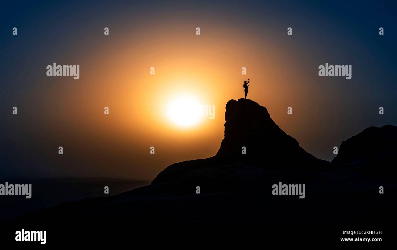 Silhouette d'un homme prenant un selfie sur la ruine d'Elliq Qala, Karakalpakstan, au coucher du soleil par temps clair Banque D'Images