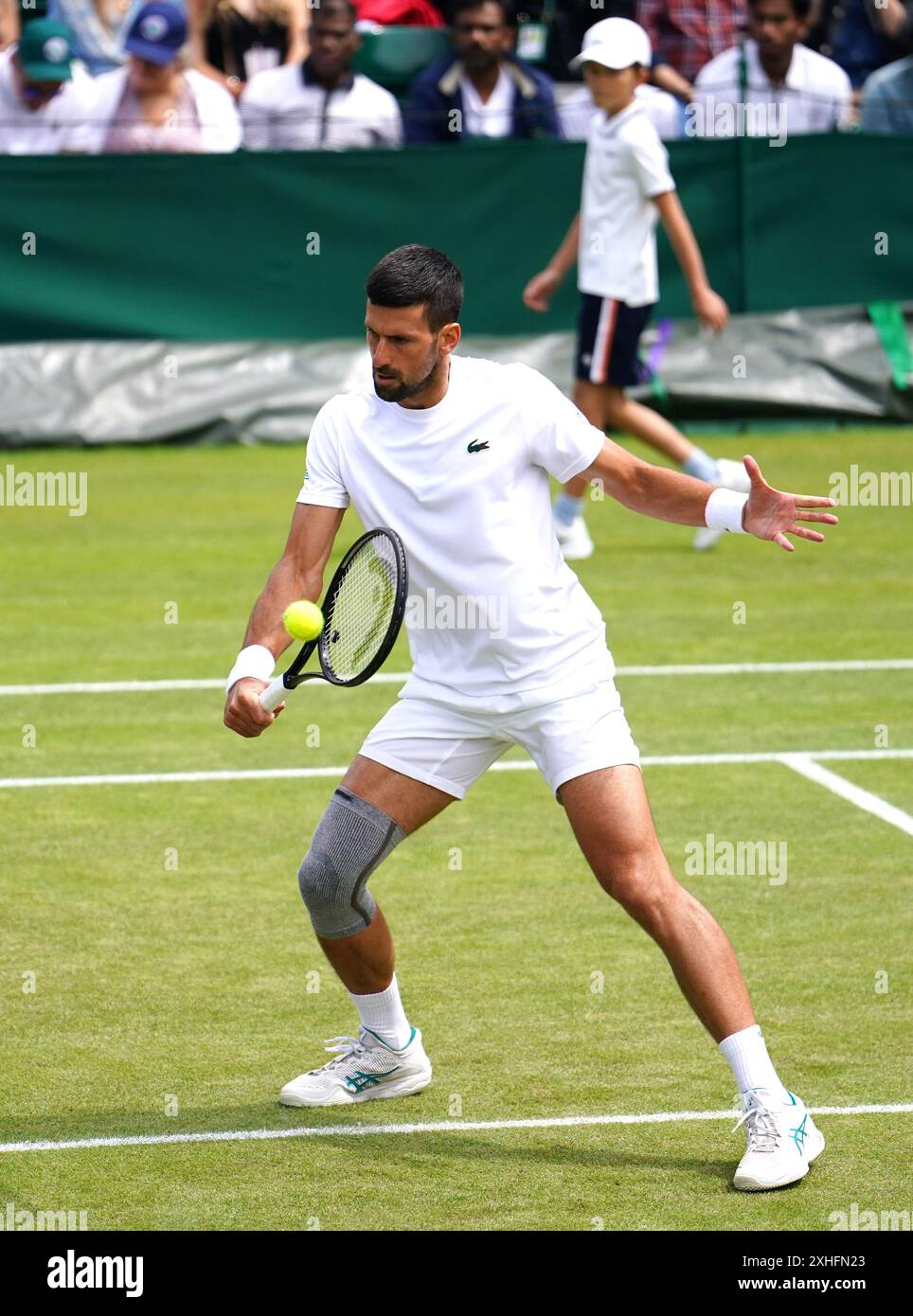 Novak Djokovic s'entraîne sur court 16 alors que son fils Stefan regarde devant la finale des Gentlemen face de Carlos Alcaraz (non représenté sur la photo) le quatorzième jour des Championnats de Wimbledon 2024 au All England Lawn Tennis and Croquet Club, Londres. Date de la photo : dimanche 14 juillet 2024. Banque D'Images