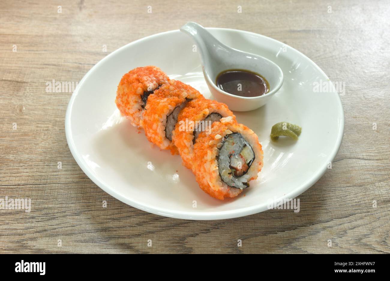 Rouleau californien nappage oeuf de crevettes riz maki sushi farci fourré oeuf sucré et concombre mariné enveloppé d'algues avec wasabi trempant la sauce soja Banque D'Images