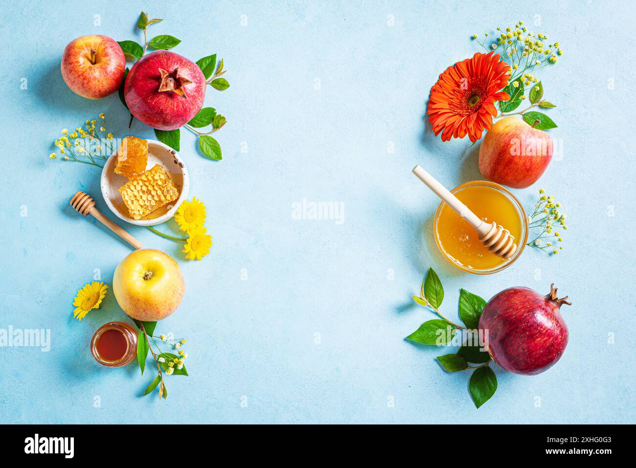 Concept de vacances du nouvel an juif Rosh Hashanah. Cadre créatif de symboles traditionnels - pommes, miel, grenade et fleurs jaunes sur fond bleu Banque D'Images