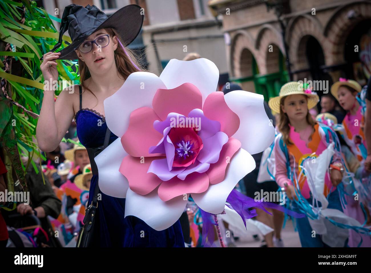 Folkestone, Kent, Royaume-Uni. 13 juillet 2024. Défilé annuel du Charivari Day. Folklore britannique et traditions rituelles sont le thème de la saisissante parade du carnaval de cette année. Des sculptures massives de tête ornent les épaules des jeunes locaux avec des enfants de l'école primaire à travers le district habillant aux couleurs du thème de l'année. Marchant du stade, en passant par la ville jusqu’au kiosque à musique Leas, le Charivari Day reste la plus grande tradition coutumière de Folkestone depuis 1997 et attire des centaines de spectateurs dans la ville portuaire en bord de mer. Crédit : Guy Corbishley/Alamy Live News Banque D'Images