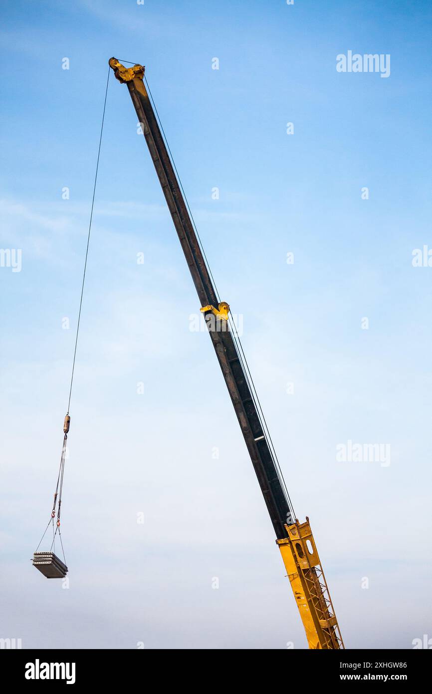 bras télescopiques jaunes de camion de grue de construction mobile soulevant la dalle de béton à la maison de construction au chantier de construction Banque D'Images