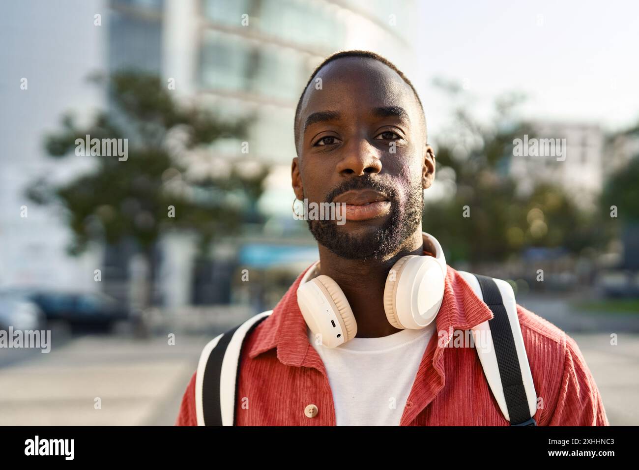 Jeune homme africain souriant debout dans la rue de la ville regardant la caméra. Portrait Banque D'Images