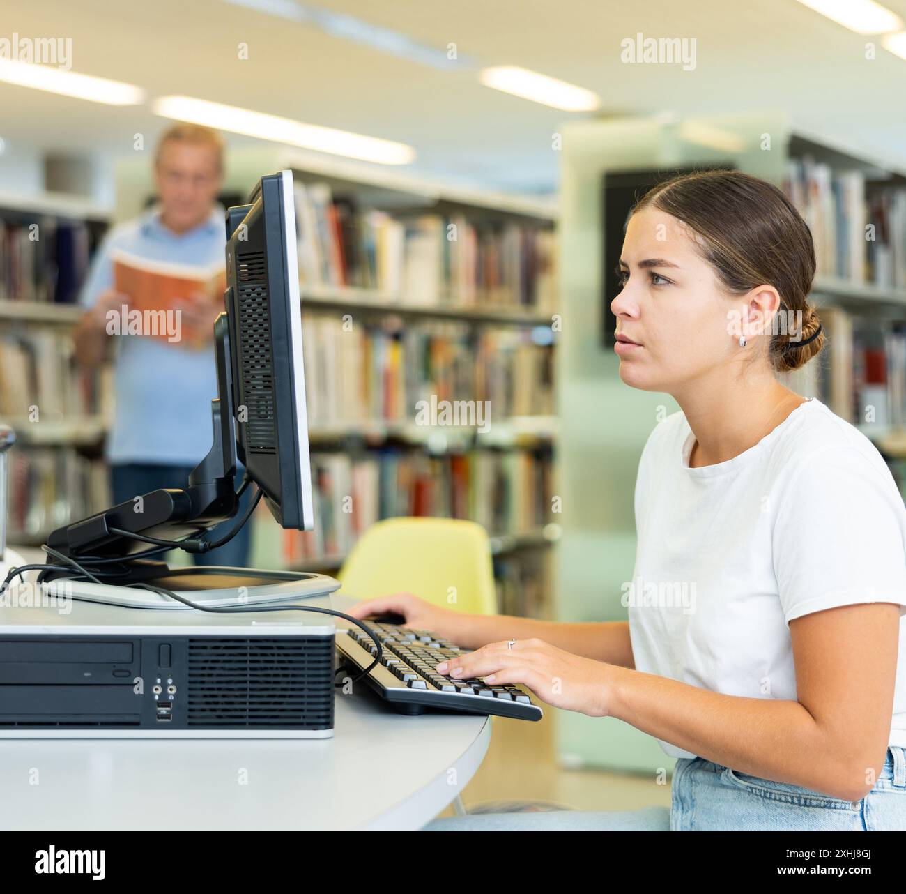 Une étudiante ciblée recherchant de l'information sur Internet sur un ordinateur fixe de la bibliothèque Banque D'Images