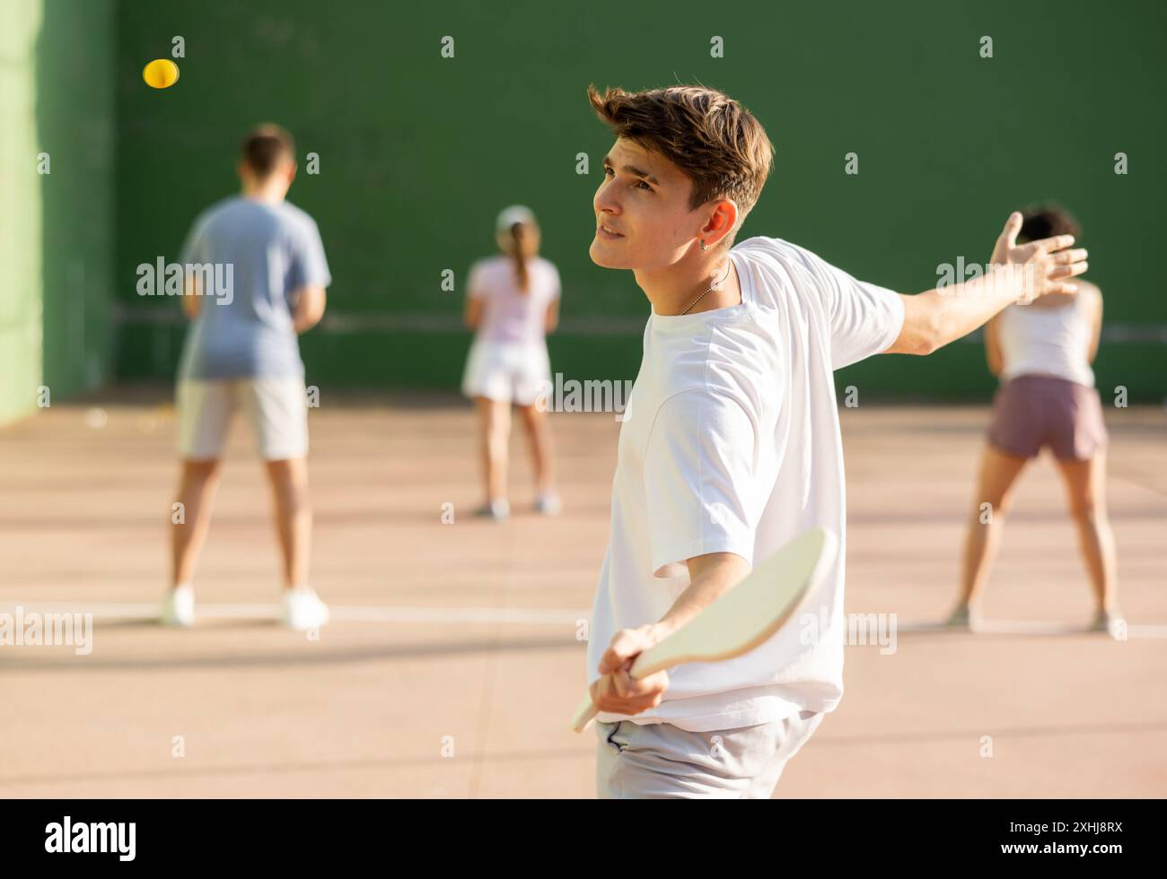 Jeune homme joueur de pelote frapper balle avec raquette en bois Banque D'Images