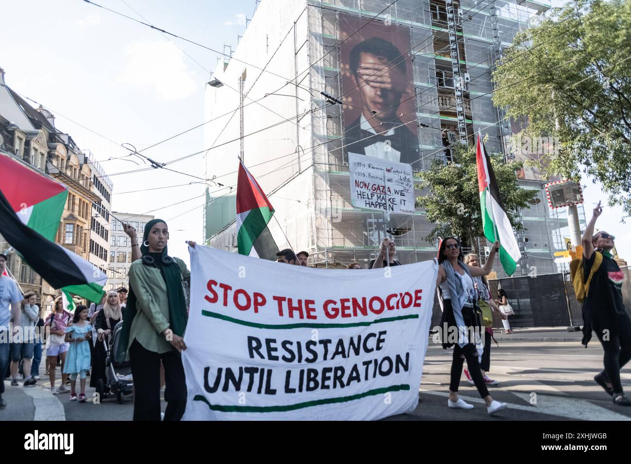 Bâle, Suisse. 13 juillet 2024. Les partisans de la Palestine tiennent une bannière et des drapeaux pendant le rassemblement. Des dizaines de personnes ont défilé dans les rues de Bâle pour une manifestation spontanée et non autorisée en faveur de la Palestine. Brandissant des drapeaux et chantant les fameux slogans comme « de la rivière à la mer », la procession a commencé à Barfüserplatz et a fait une tournée d’une heure et demie à travers la ville. (Photo de Matteo Placucci/SOPA images/SIPA USA) crédit : SIPA USA/Alamy Live News Banque D'Images