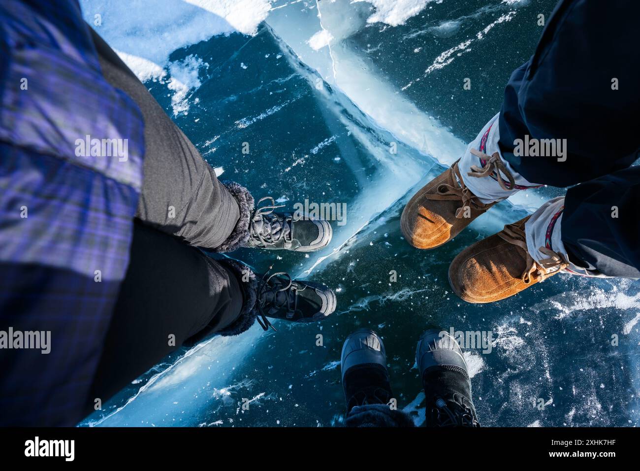 Trois personnes se tiennent sur la glace arctique sur la route des glaces menant à l’exploitation minière de diamants à Yellowknife, au Canada Banque D'Images