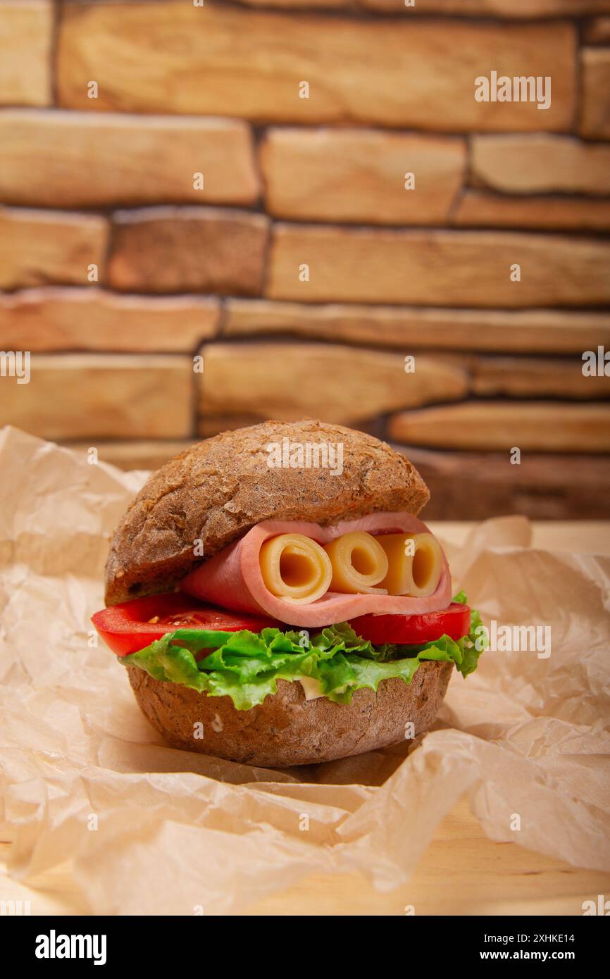 Sandwich avec jambon, fromage, tomates, laitue et pain rond d'orge au fond de mur de briques Banque D'Images
